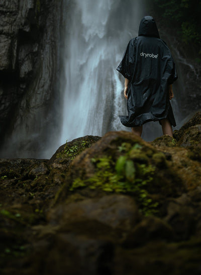 Person walking towards waterfall wearing dryrobe® Lite 