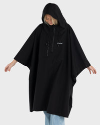 Woman wearing Black dryrobe® Waterproof Poncho with hood up, looking down 