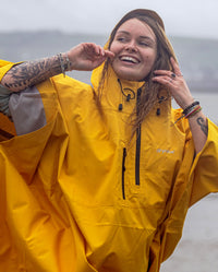 Close up of woman smiling in the rain, wearing  Yellow dryrobe® Waterproof Poncho