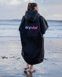 Girl walking towards the sea wearing Black Pink dryrobe® Advance Kids Long Sleeve