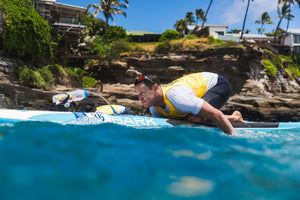 A man paddleboarding in bright blue waters in Hawaii 