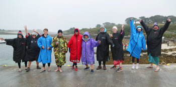 A group of swimmers stood in dryrobe® Advance change robes on the beach 