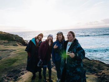 A group image of four people smiling next to the coast 