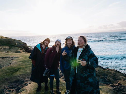 A group image of four people smiling next to the coast 
