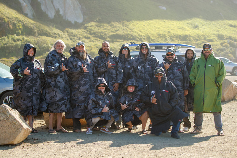 Operation Surf veterans posing for group photo in Black Camo Dryrobe Advances at the beach