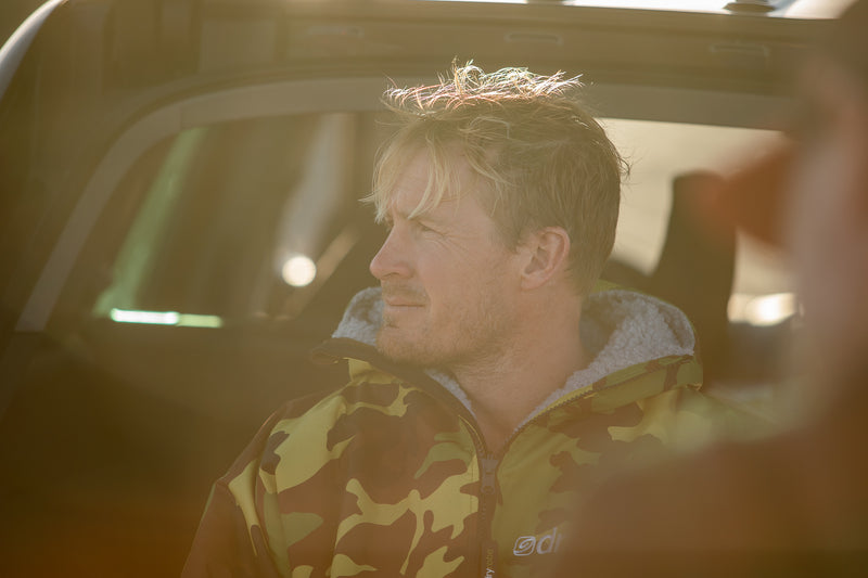 Andrew Cotton looking out to the ocean wearing a green camo dryrobe® Advance 