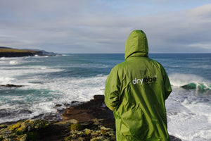 A person looking out to sea in a green dryrobe