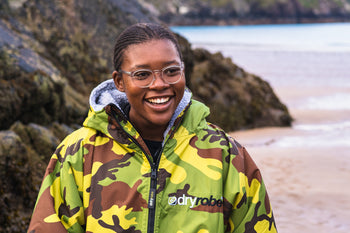 Sne Makhuhu smiling on the beach and wearing a Camo dryrobe® Advance change robe 