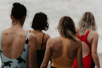 Swimmers walking into the sea at the beach in swimming costumes 