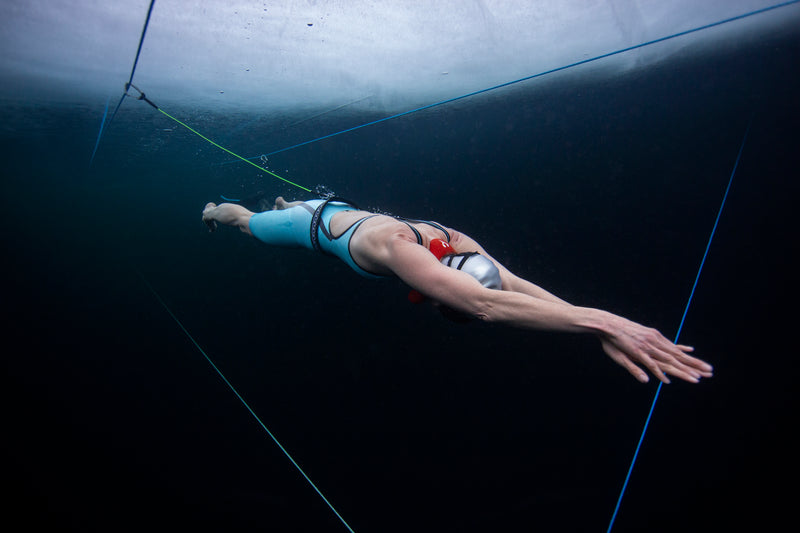 A woman swimming under the ice in a lake 