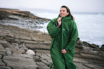 Lucy Campbell smiling and zipping up a green dryrobe Advance by the sea 