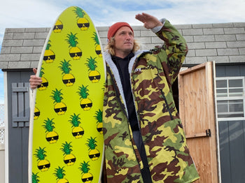 Ben Gravy holding a punk pineapple branded sponge board wearing a camo dryrobe®