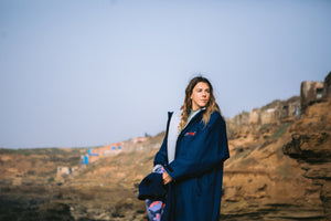 Lucy Campbell in a dryrobe holding a wetsuit 