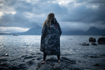 best changing robe blog image featuring model wearing a black camo dryrobe advance looking across the sea 