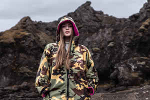 A woman wearing a Camo Pink Dryrobe stood in front of rocks