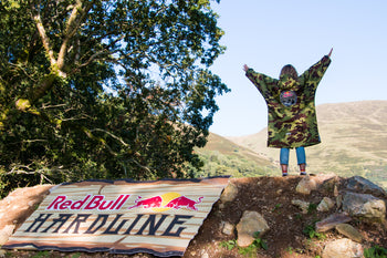 A woman stood next to the Red Bull Hardline sign with her hands in the air in a Limited Edition Red Bull Hardline dryrobe® Advance 