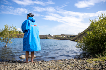 A woman stood in a blue changing robe getting ready to swim in a lake
