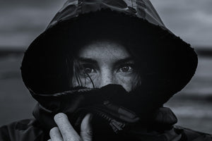 Dramatic black and white close-up of pro surfer Lucy Campbell’s eyes peeking out from a hooded Dryrobe® changing robe