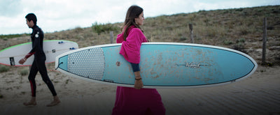 Young person holding a surfboard wearing Pink Organic Cotton Towel dryrobe®