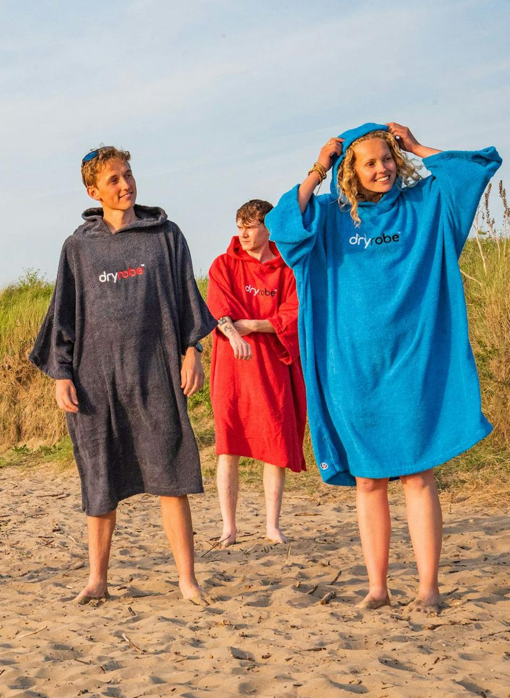 Group of adults wearing Dryrobe organic towel robe on a beach