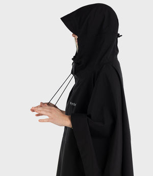 Woman stood facing sideways, wearing Black dryrobe® Waterproof Poncho