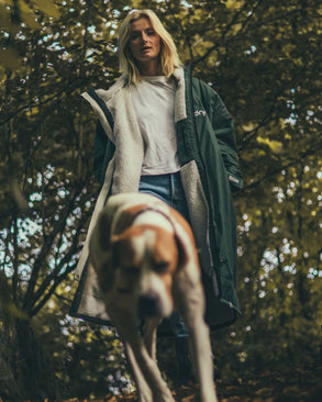 Female walking under trees with dog  wearing AW25 Green Dryrobe® advance long sleeve 