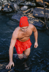 Man wearing swimming shorts and dryrobe® Eco Beanie, stepping out of a stream