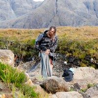 Male wearing black camo Dryrobe® getting changed in front of mountain