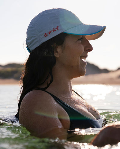 Woman swimming in water wearing grey Dryrobe® water resistant cap 