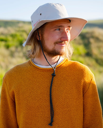 Male by the coast wearing grey Dryrobe® water resistant wide brimmed hat 