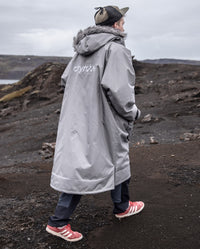 Man walking along cliff away from camera, wearing dryrobe Advance Long Sleeve Alpine Range change robe in Alpine Graphite 