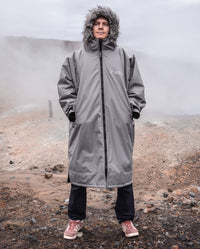 Man stood on misty hill, wearing dryrobe Advance Long Sleeve Alpine Range change robe in Alpine Graphite with hood up