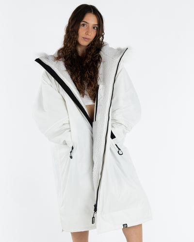 Woman wearing dryrobe Advance Long Sleeve Alpine Range change robe in Alpine White with hands in pockets 
