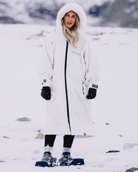 Woman stood in snow, wearing dryrobe Advance Long Sleeve Alpine Range change robe in Alpine White