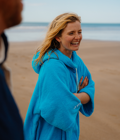 Woman wrapped in a blue towel robe on a beach