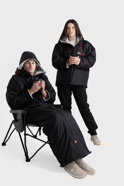 Two people wearing black Dryrobe® with hoods on a white background
