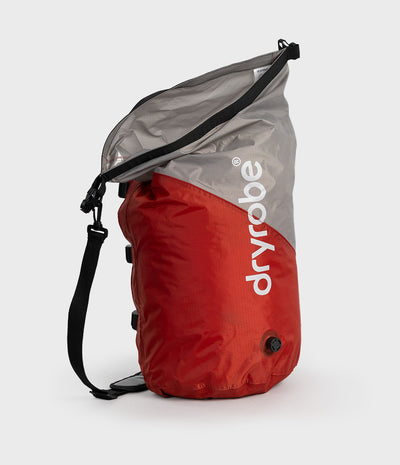 A red and gray Dryrobe waterproof bag with a black strap, shown on a light gray background.
