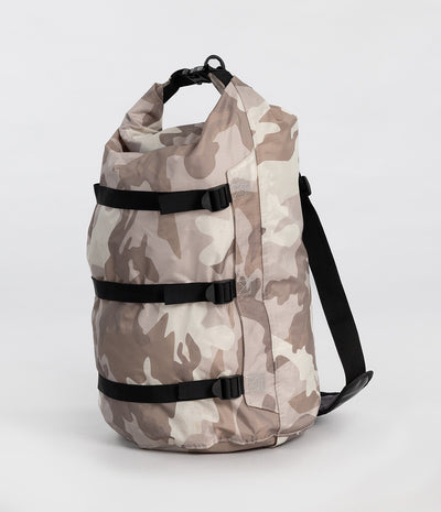 A roll-top Dryrobe compression bag. in a beige and brown camouflage pattern, featuring three black compression straps and a black shoulder strap, set against a plain light gray background.