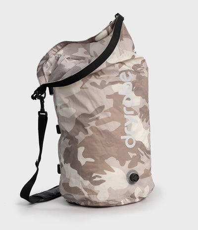 A roll-top Dryrobe compression bag. in a light beige and brown camouflage pattern, featuring a white 'dryrobe' logo on the side and black straps, set against a plain light gray background.