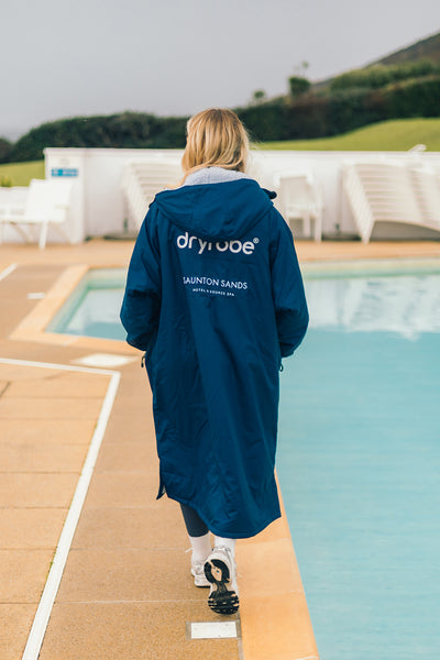 Person wearing a blue 'Dryrobe® Advance Change robe by a poolside