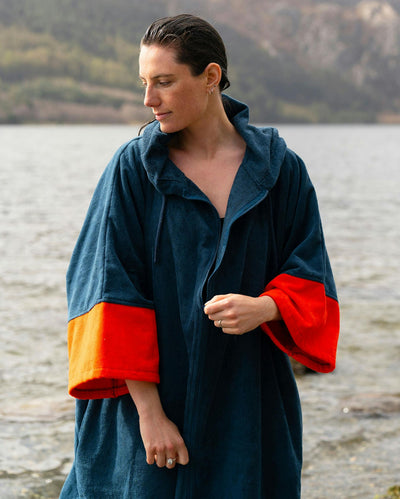 Female by water wearing Dryrobe® Zip towel (blue orange)