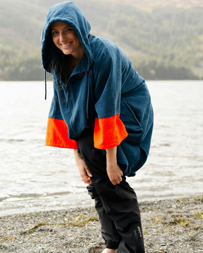 Female by water wearing Dryrobe® Zip towel (blue orange)