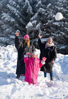 Three people playing in the snow with trees in the background