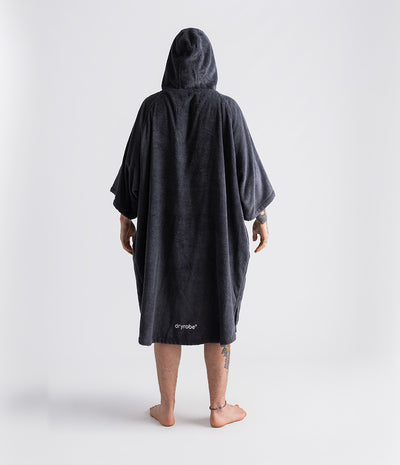 *MALE* Person wearing a dark grey hooded poncho with 'dryrobe' branding on a white background