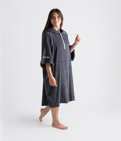Woman wearing a dark gray dryrobe with a white logo on a white background