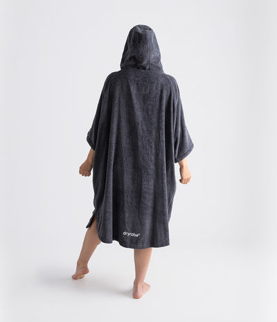 Person wearing a dark grey hooded towel robe with 'Dryrobe' branding on a white background