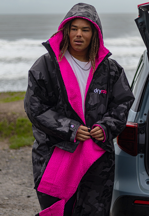 surfer wearing a black camo pink dryrobe in the cold