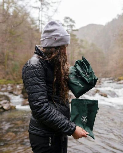 *MALE* Adult packing Dryrobe® green poncho in front of river
