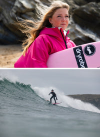 Person in pink jacket holding a pink surfboard with 'dryrobe' branding, followed by a surfer in black wetsuit on a wave.