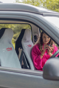 Person in a pink robe sitting inside a car.